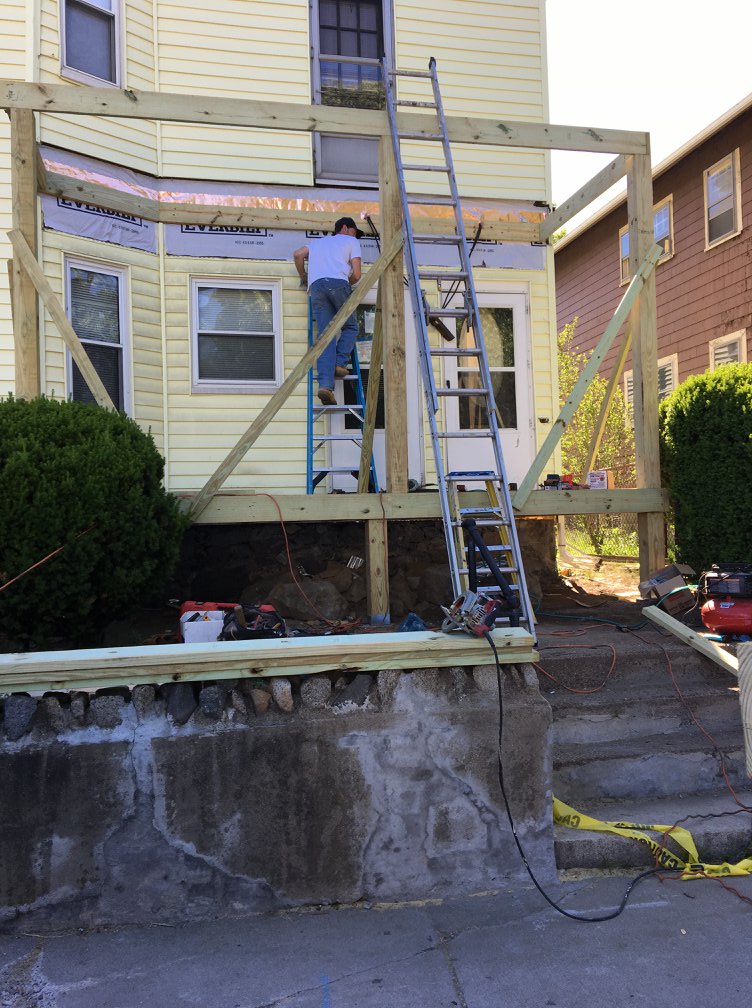 Worker on ladder during porch and deck construction project